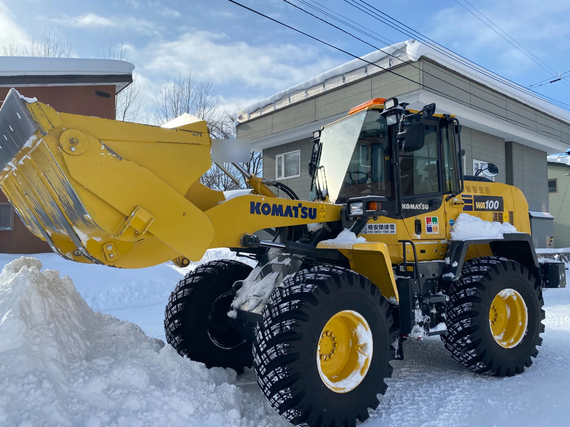 積雪した住宅地で除雪作業を行うホイールローダー